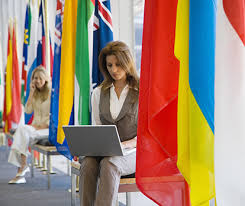 due ragazze tra alcune bandiere lavorano al loro laptop